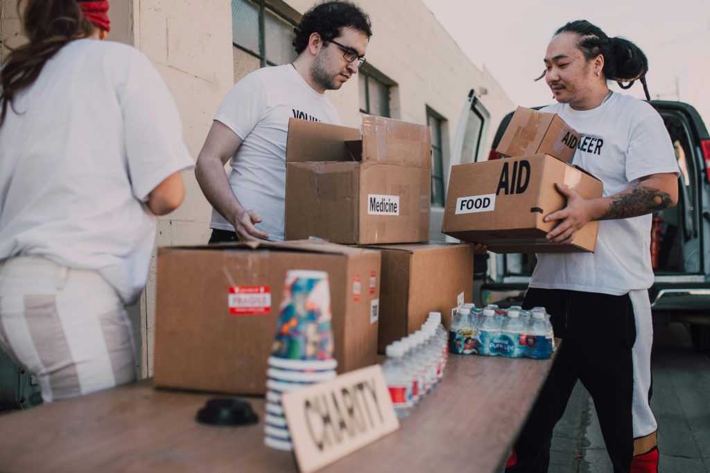 Get Involved Volunteers loading aid boxes with food and medicine from a van outdoors.